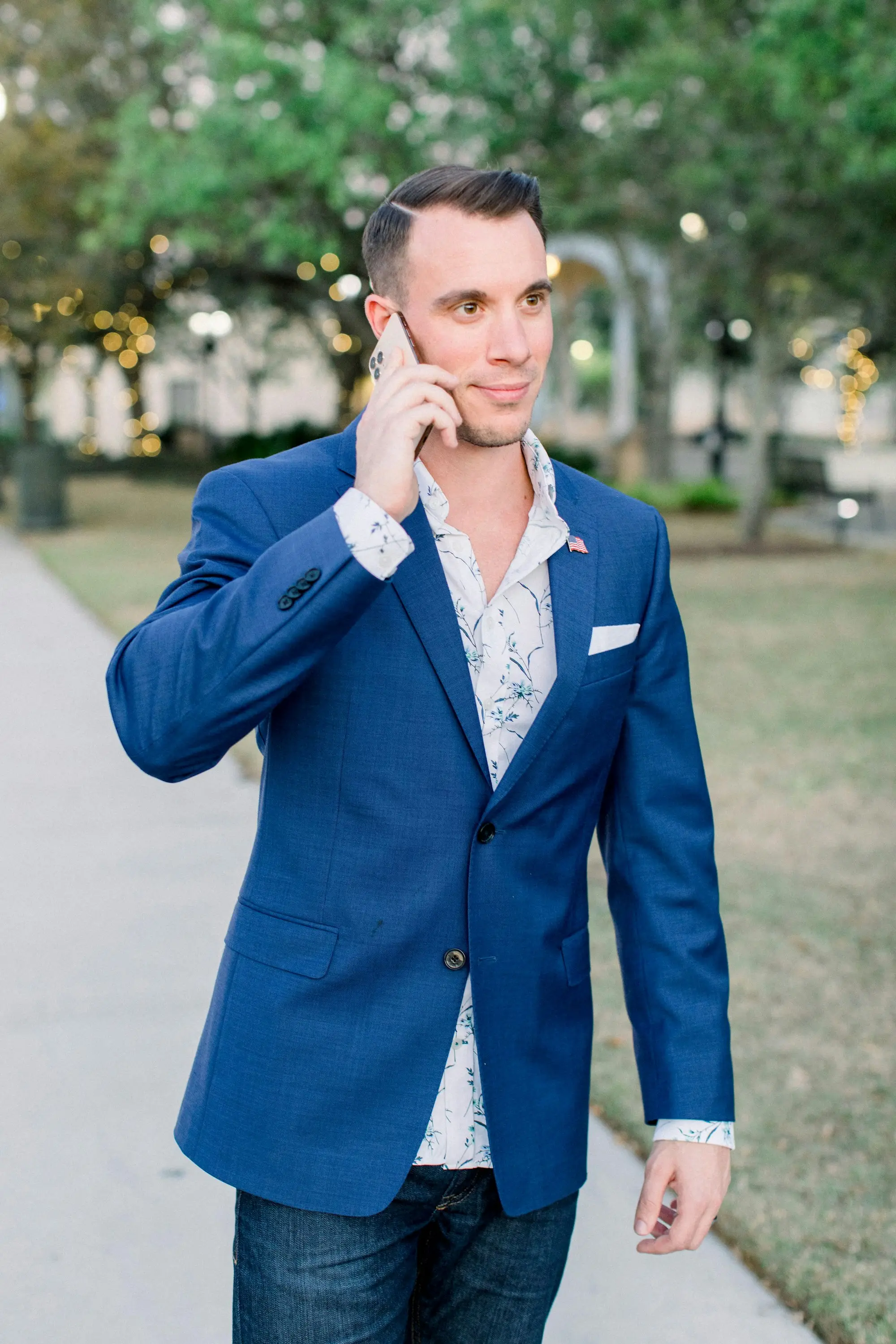Professional services owner in a blue blazer taking a call while walking through a leafy park