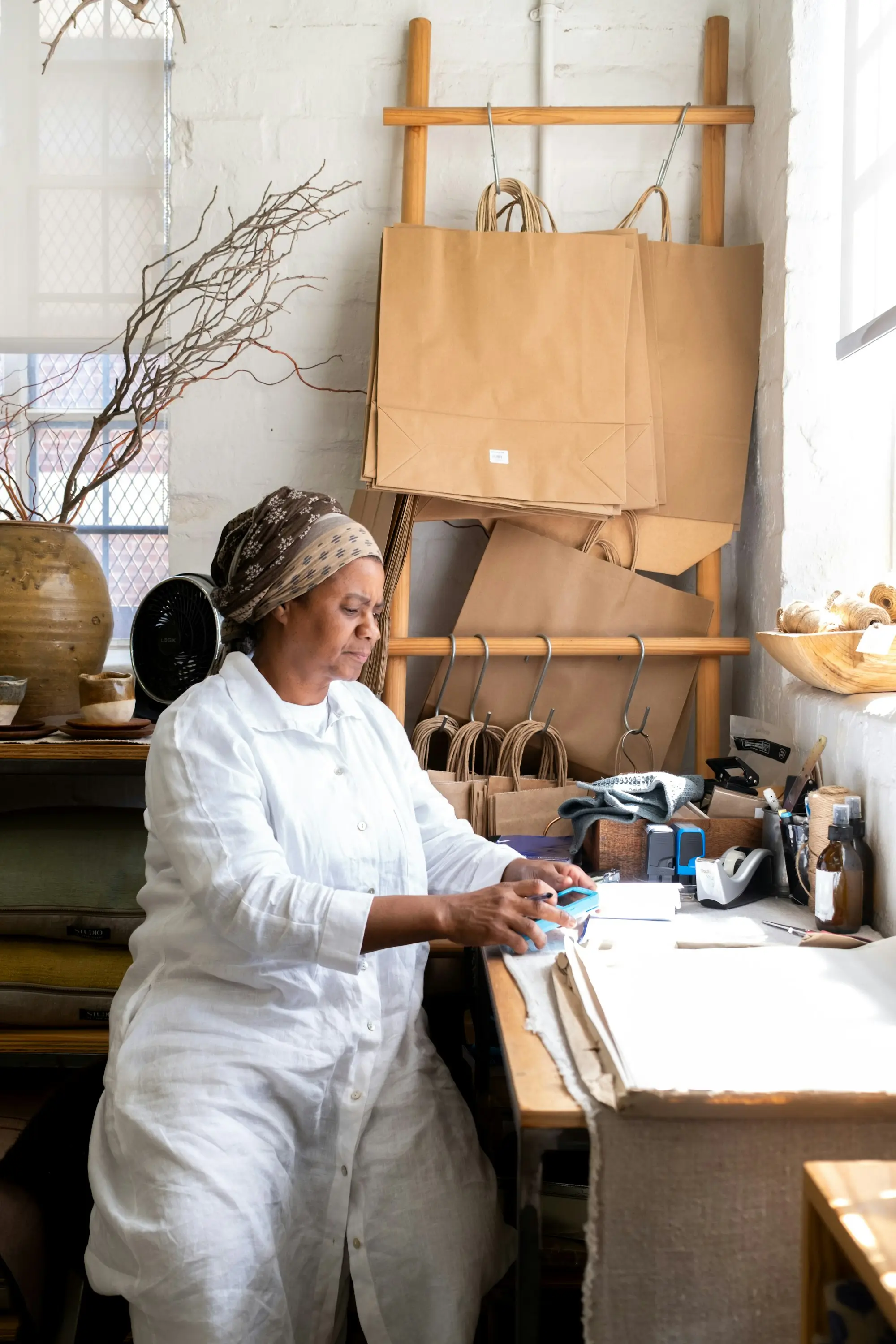 Maker in a white work suit preparing orders at a bench in her small craft workshop