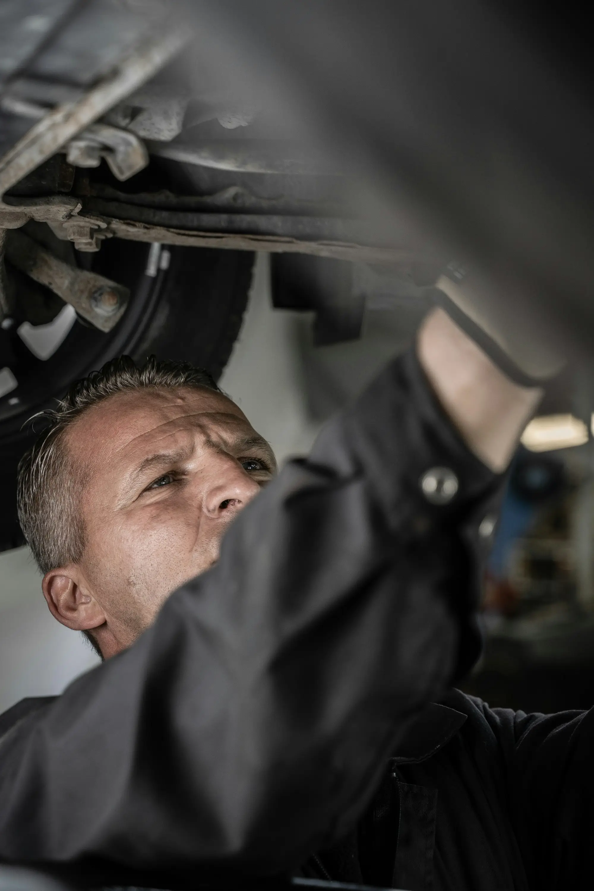 Mechanic working on the underside of a car raised on a hoist