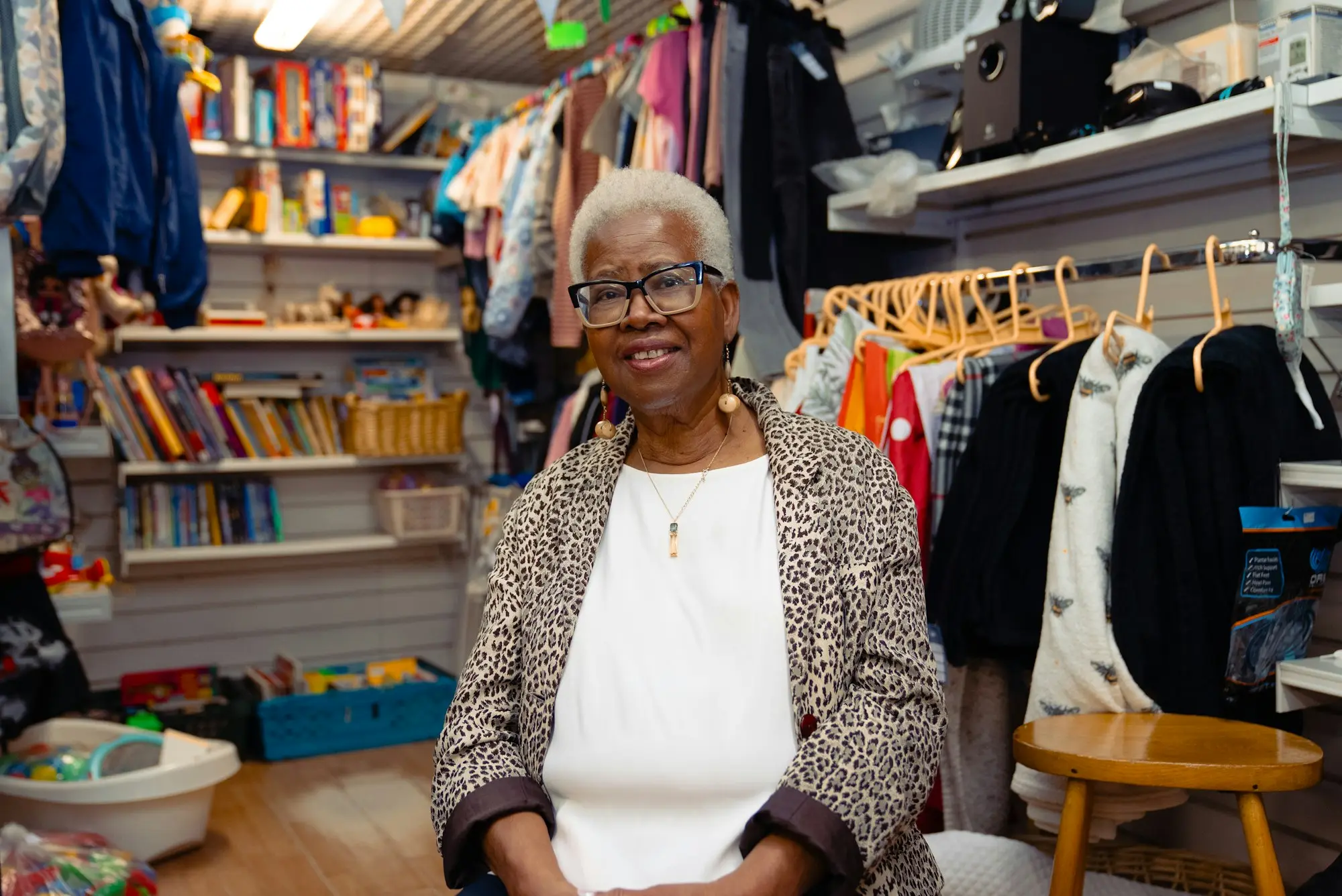 Shop owner smiling in her store surrounded by clothing racks and shelves of books
